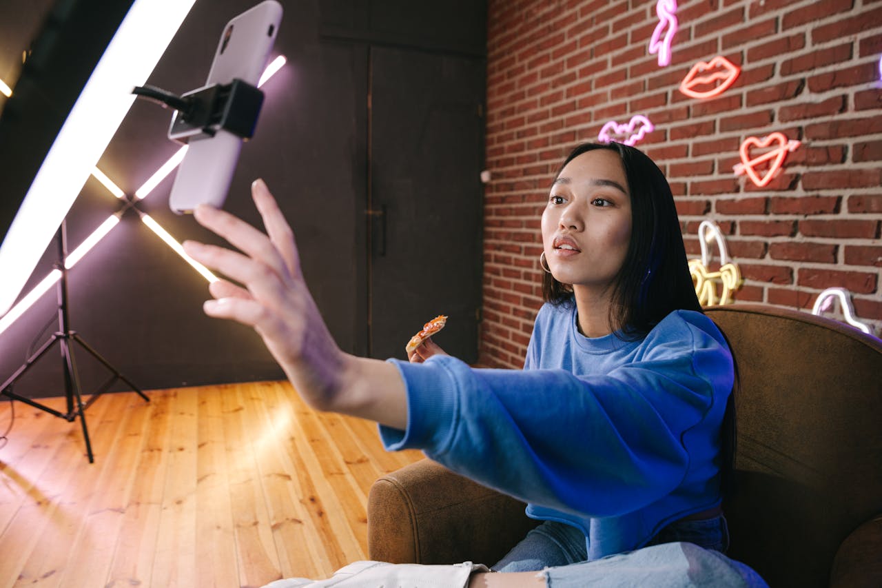 gallery-6 Asian woman creates live stream content in stylish neon lit room.